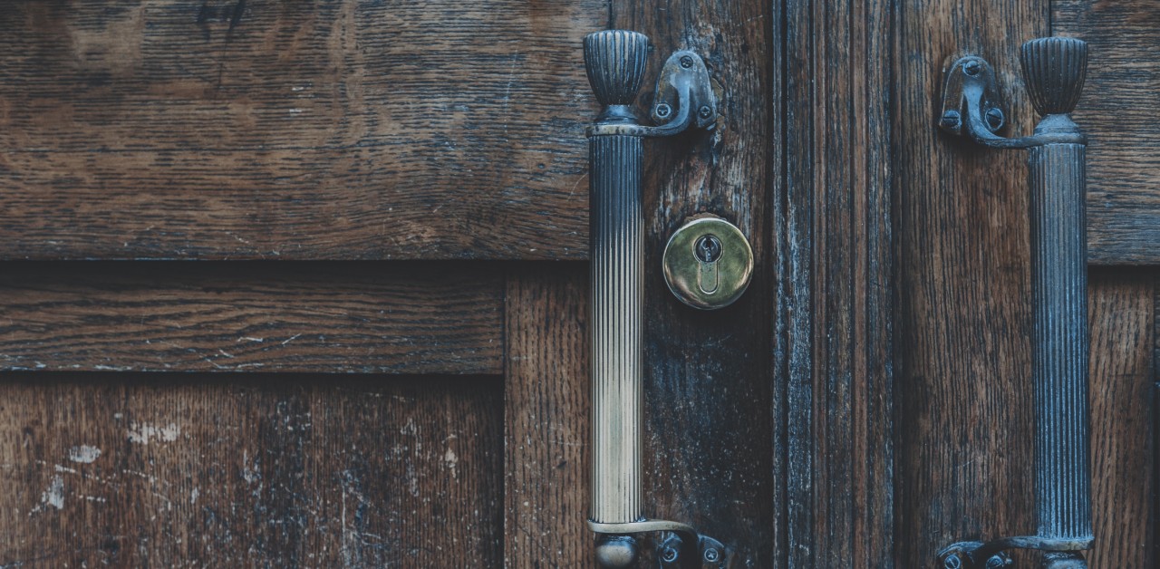 An image of dark wood doors with handles.