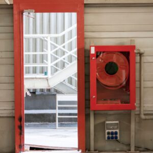 an emergency door that is open and a fire hose on the wall