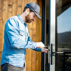 man repairing locking mechanism on commercial door