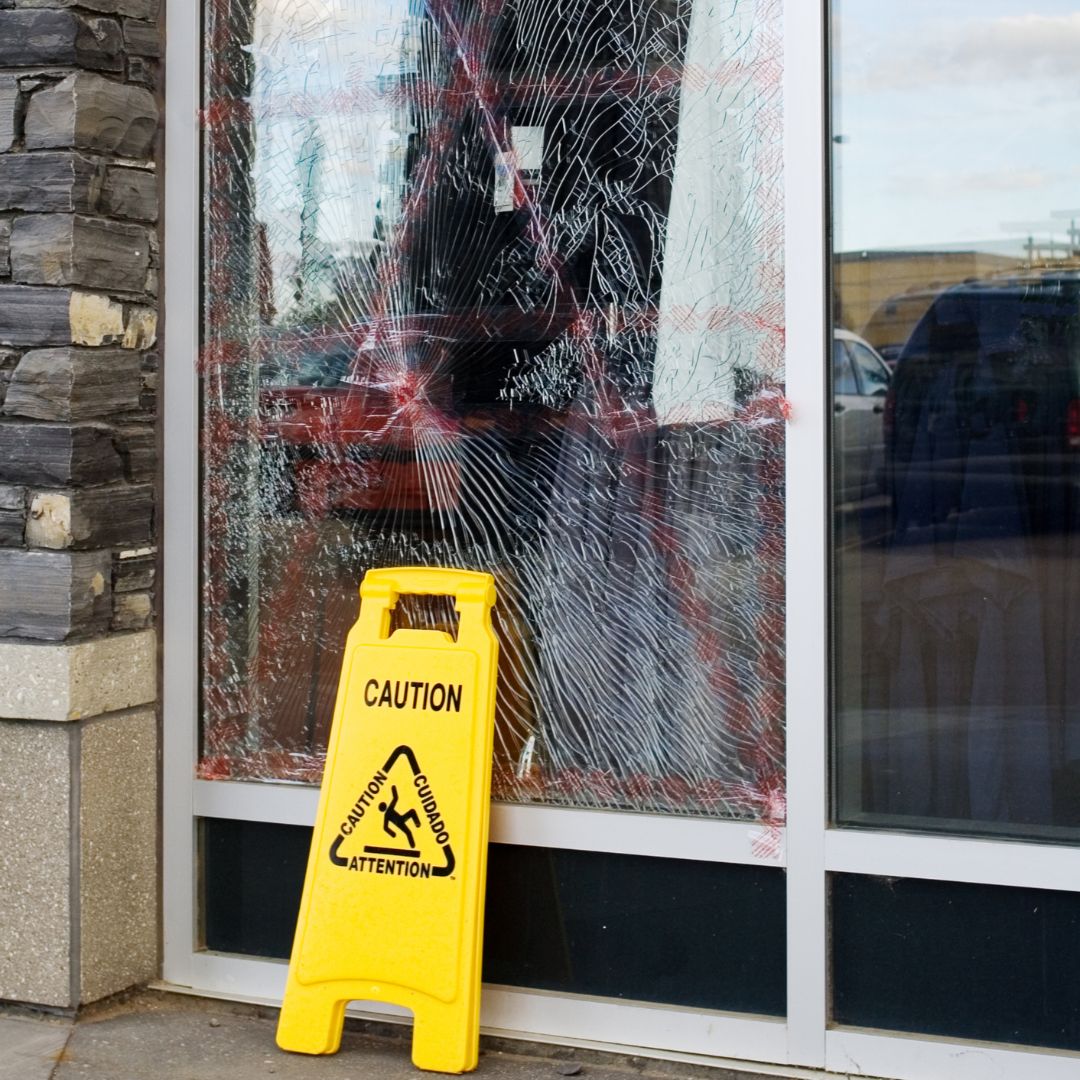 caution sign in front of broken glass window